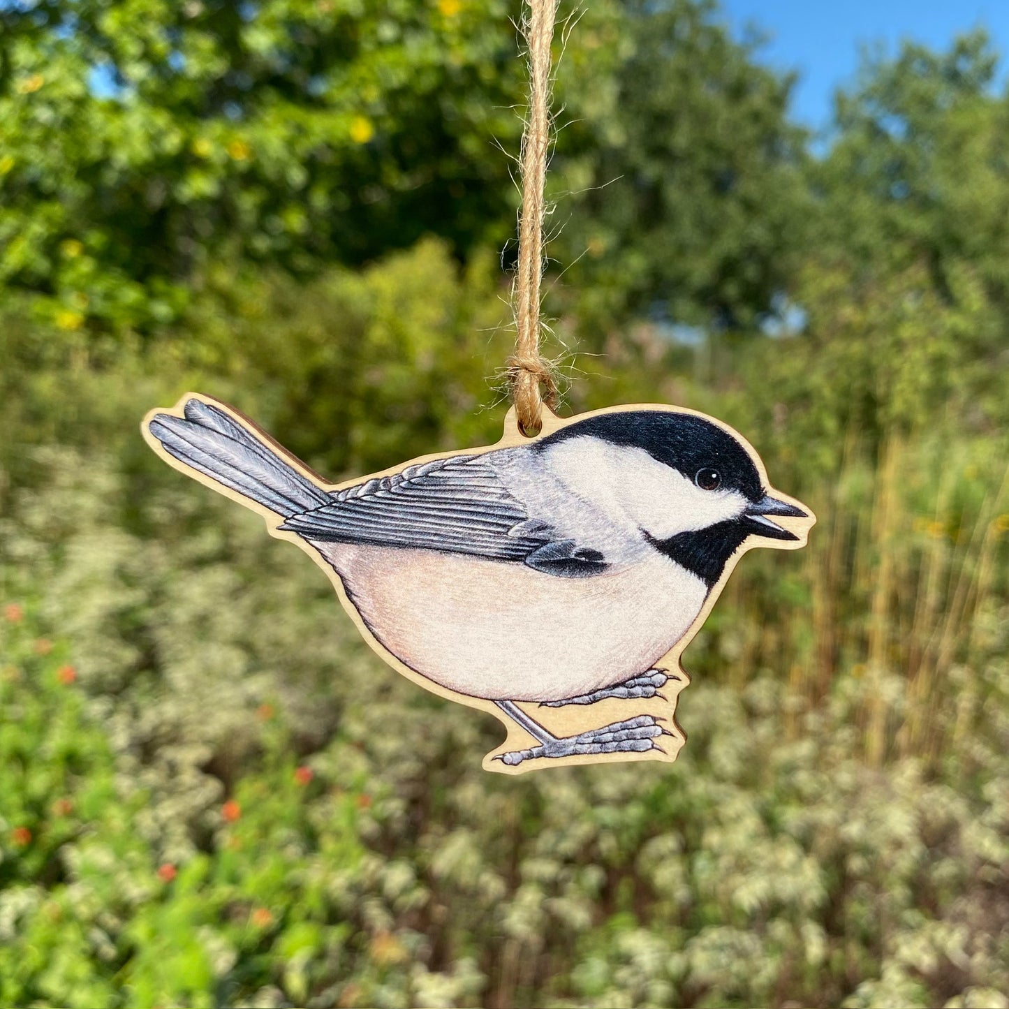 A wooden ornament strung with twine of a Carolina chickadee.