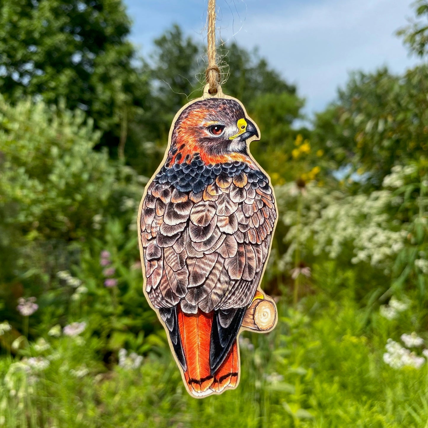 A wooden ornament strung with twine of a red-tailed hawk.