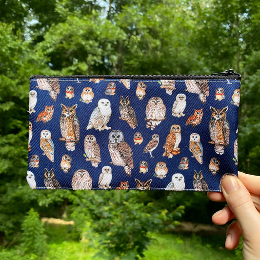 A hand holding a navy pouch with a pattern of owls on it.