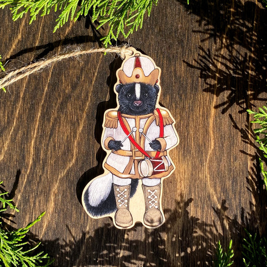 A wooden ornament strung with twine of a skunk in a white nutcracker outfit.
