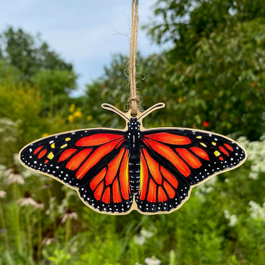 A wooden ornament strung with twine of a monarch butterfly.