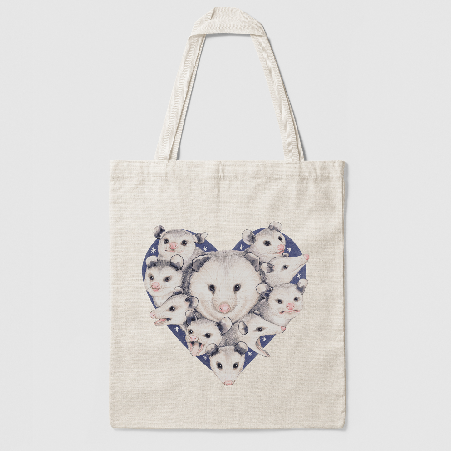 A tote bag of a mom opossum surrounded by her babies with a starry heart background.