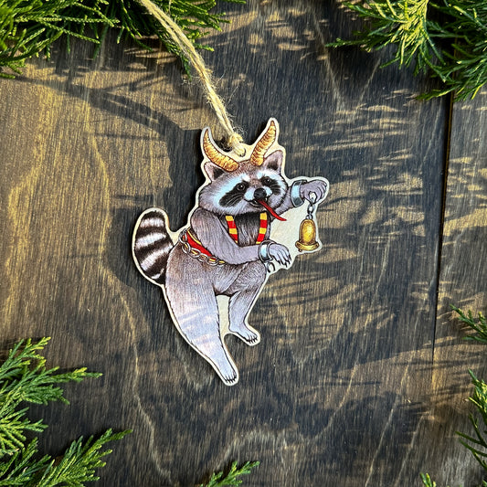 An ornament of a raccoon dressed up as Krampus holding a bell.