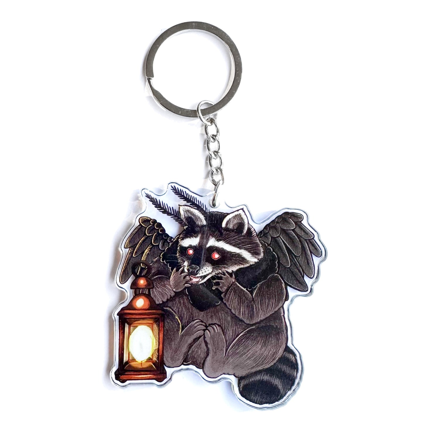 A double-sided acrylic keychain featuring an illustration of a Mothman Raccoon holding a lantern.