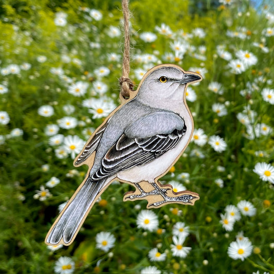 Northern mockingbird ornament hanging in front of white flowers
