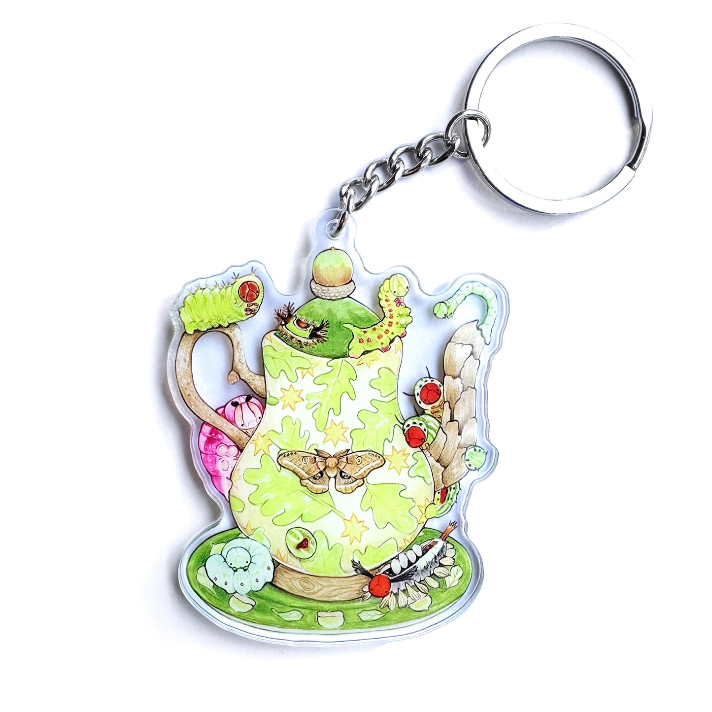 A double-sided acrylic keychain featuring an illustration of a caterpillar teapot with oak leaves and a moth design.