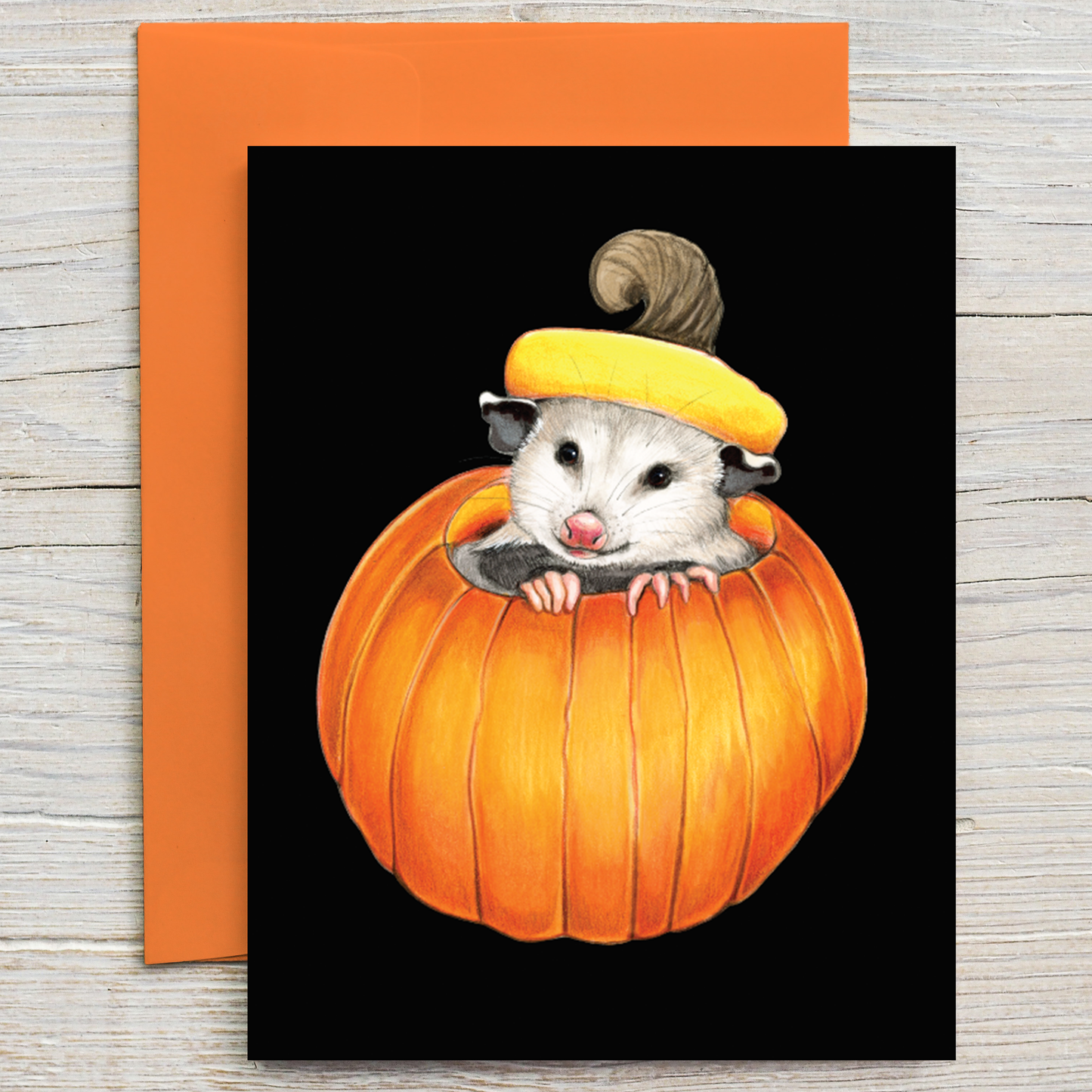 A Halloween, fall, or autumn greeting card showing an opossum peeking out of a pumpkin.
