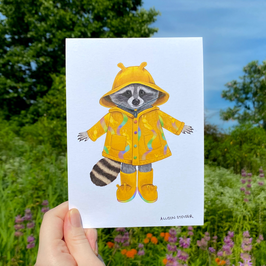 Illustration of a raccoon in a yellow raincoat held in front of a natural background with trees and flowers.
