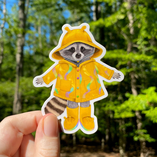 A sticker of a raccoon in a yellow rain coat with banana slugs leaving rainbow slime trails.