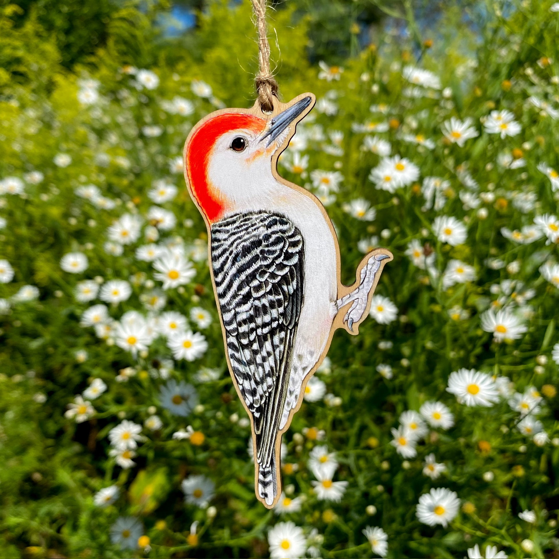 Red-bellied woodpecker ornament hanging against a background of flowers and greenery