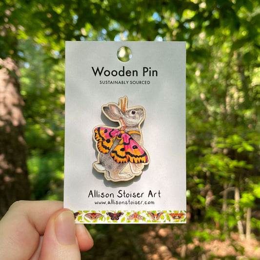 A wooden pin of a cottontail rabbit with sheep moth wings on packaging that reads Wooden Pin, Sustainably Sourced.