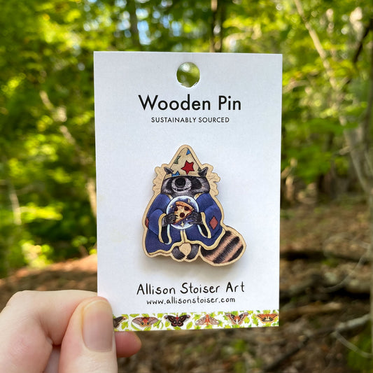 Wooden pin of a raccoon wizard on a card with a forest background