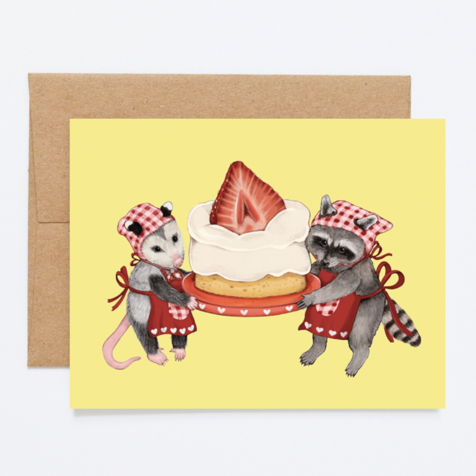 A card with a raccoon and opossum holding a strawberry cake