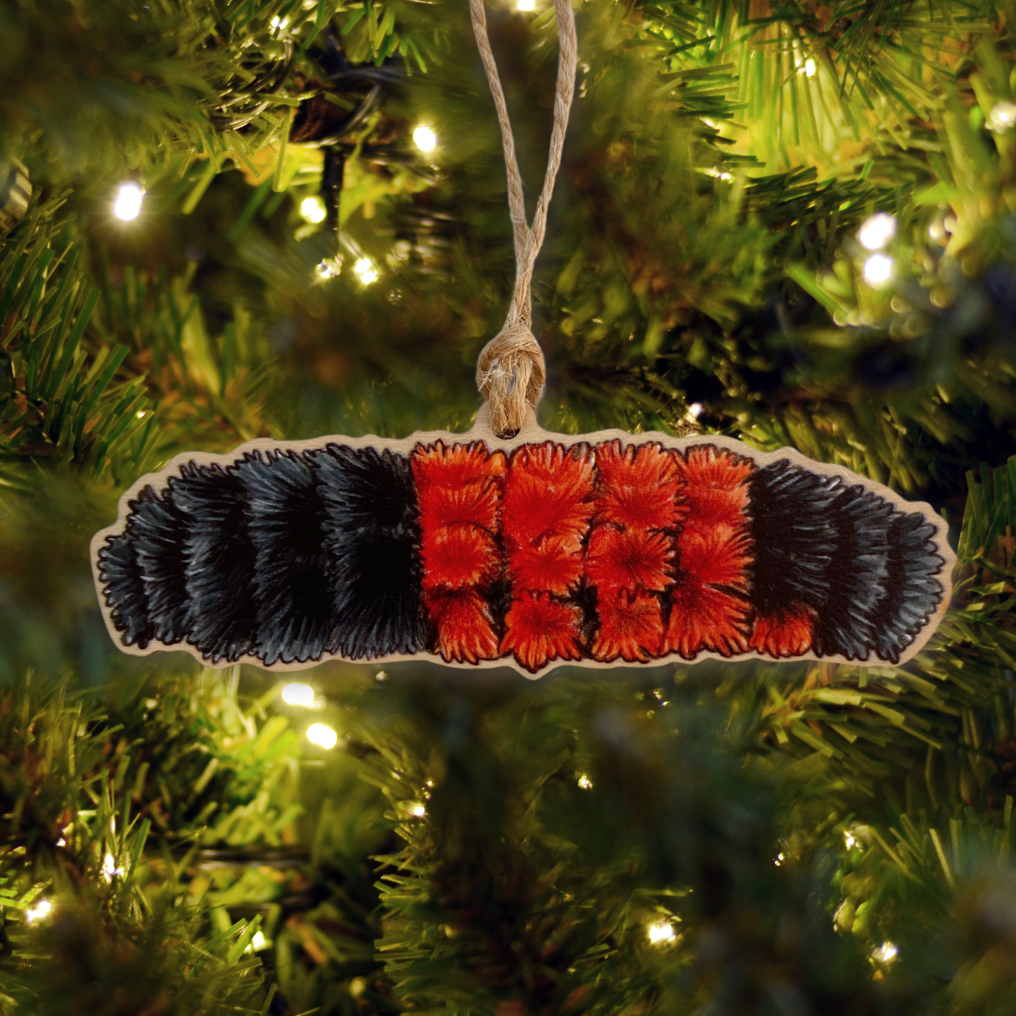 Decorative ornament of a woolly bear caterpillar hanging on a Christmas tree.