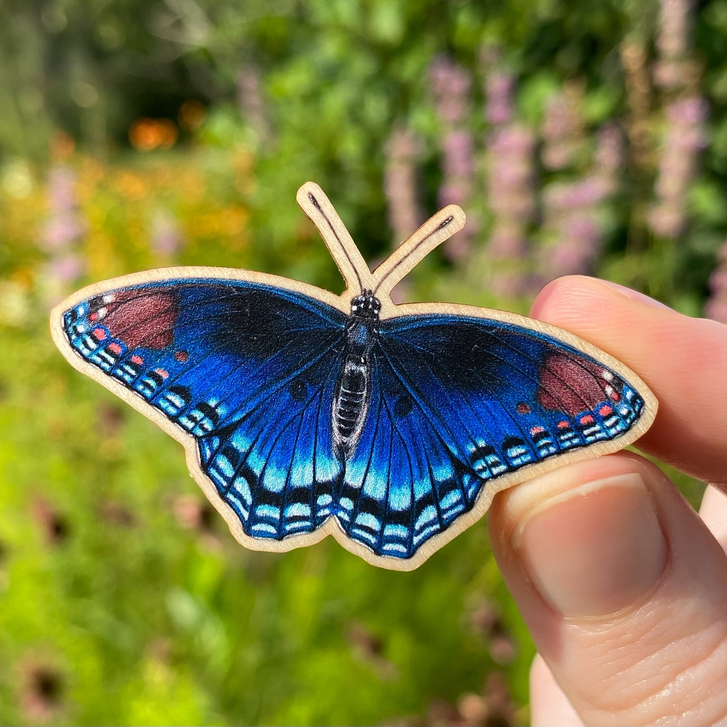 A sustainably sourced wooden pin featuring a red-spotted purple butterfly