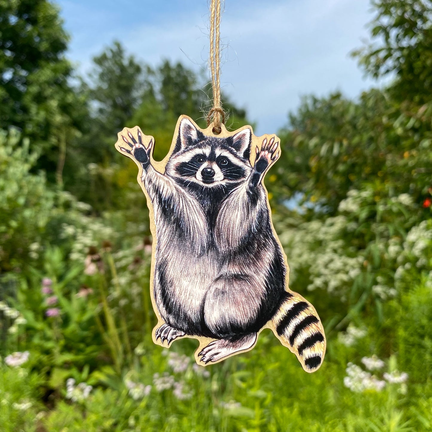 A wood print ornament featuring an illustration of a raccoon