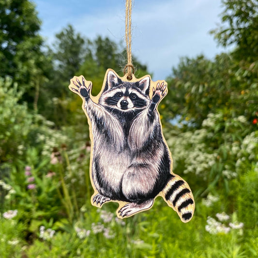 A wood print ornament featuring an illustration of a raccoon