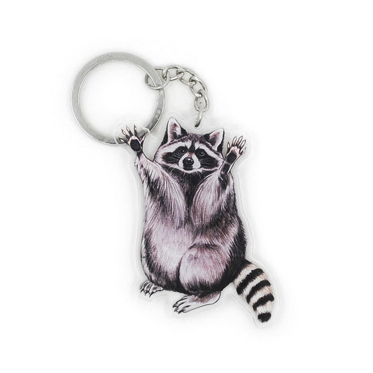 A keychain of a raccoon with its arms raised on a white background.