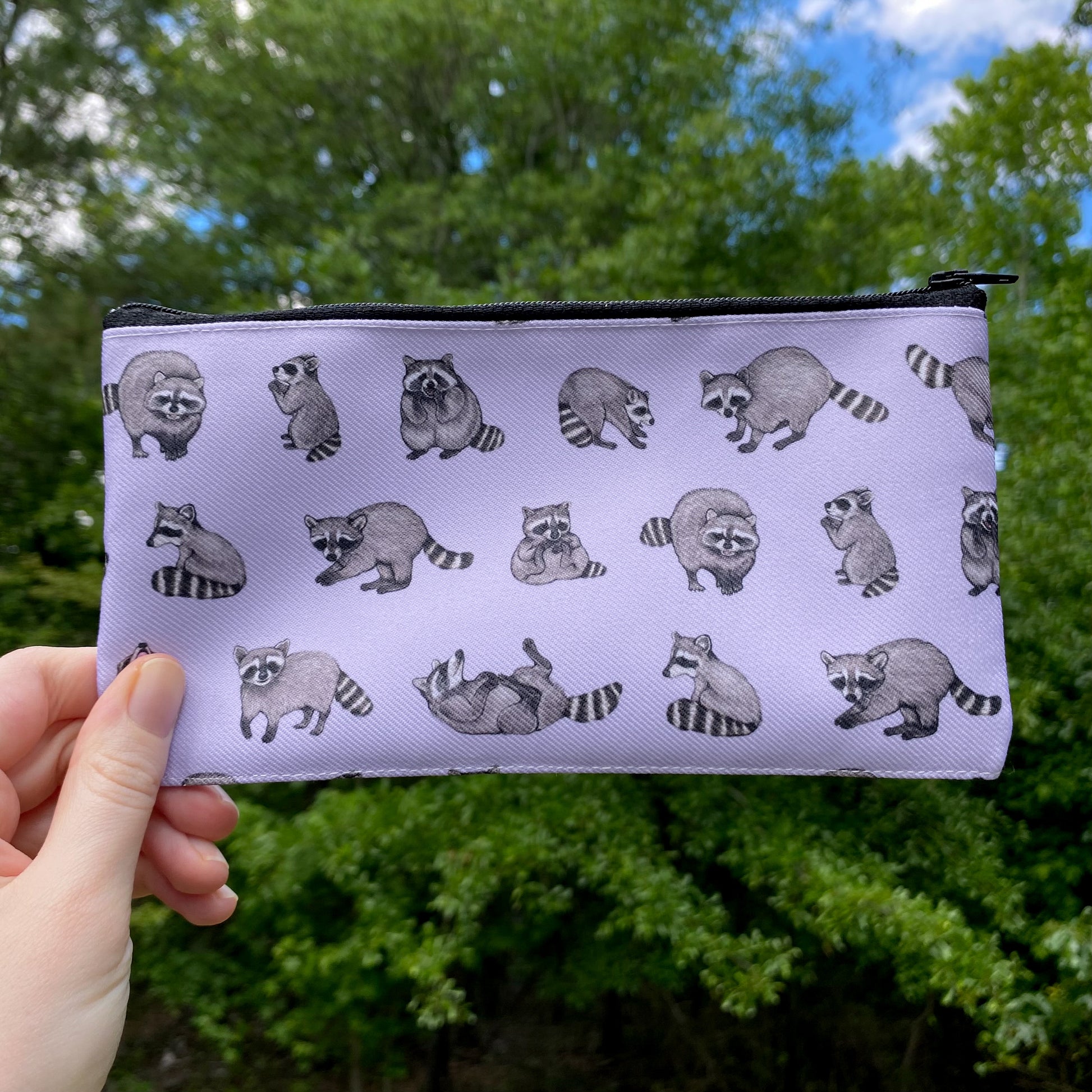 a purple zippered pouch with a repeat pattern of raccoons