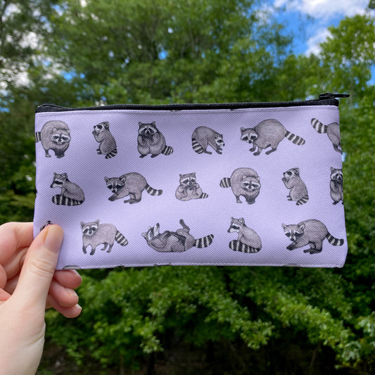 a purple zippered pouch with a repeat pattern of raccoons