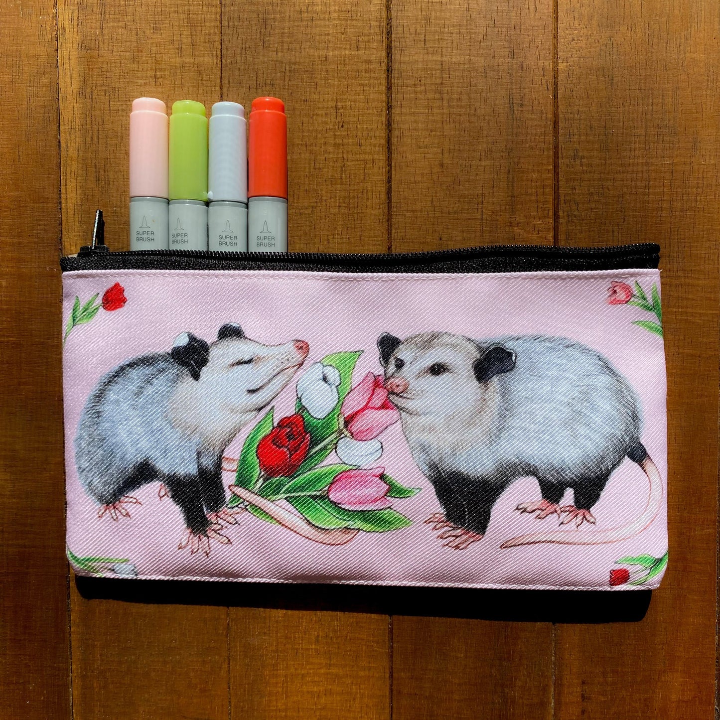 A zippered pouch featuring opossums and tulips