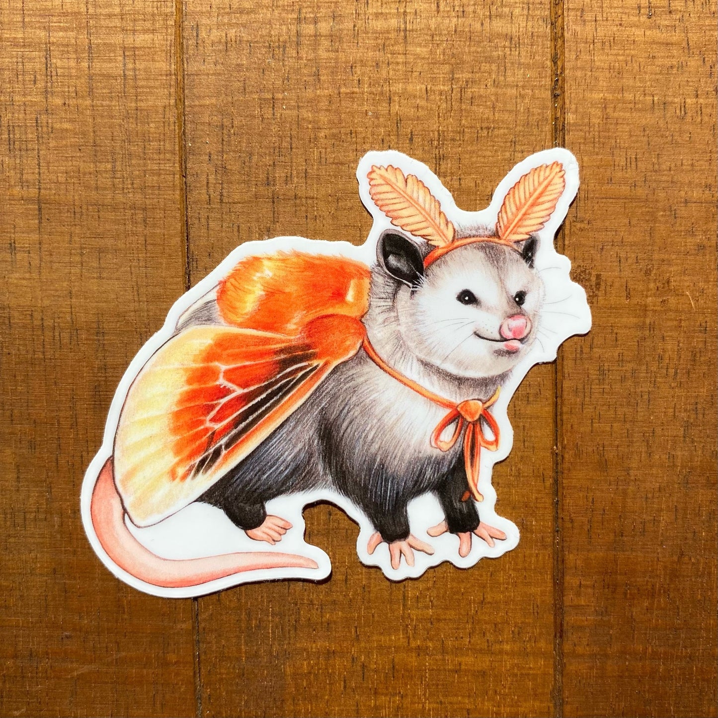 A weatherproof vinyl sticker featuring an illustration of an opossum dressed as a flannel moth