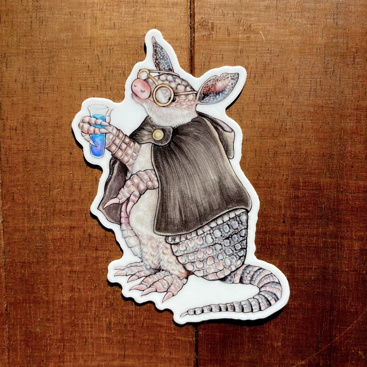 A sticker featuring an illustration of an armadillo working as an alchemist