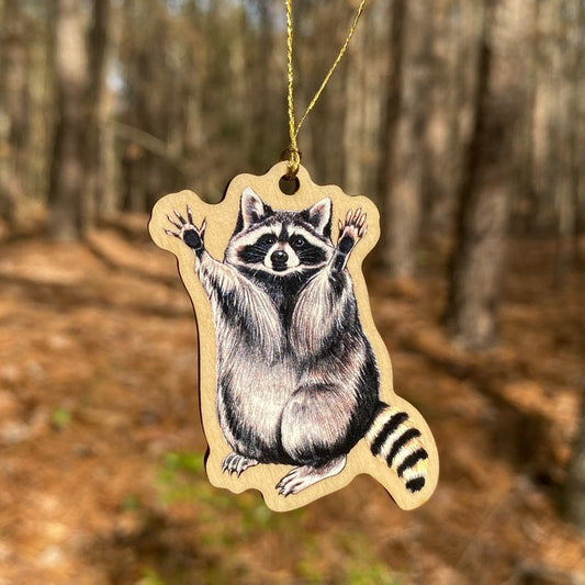 A wood print ornament featuring an illustration of a raccoon
