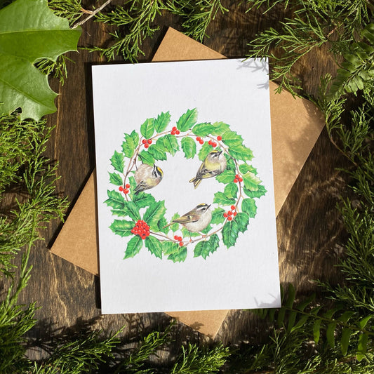 A card featuring a holly wreath with golden-crowned kinglets perched within