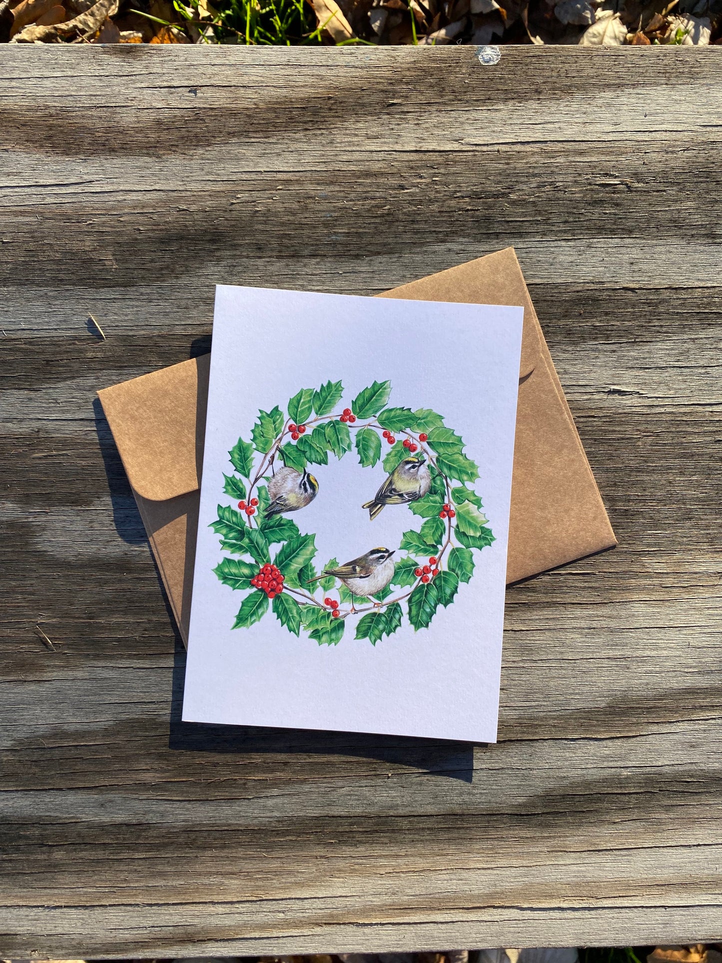 A card featuring a holly wreath with golden-crowned kinglets perched within
