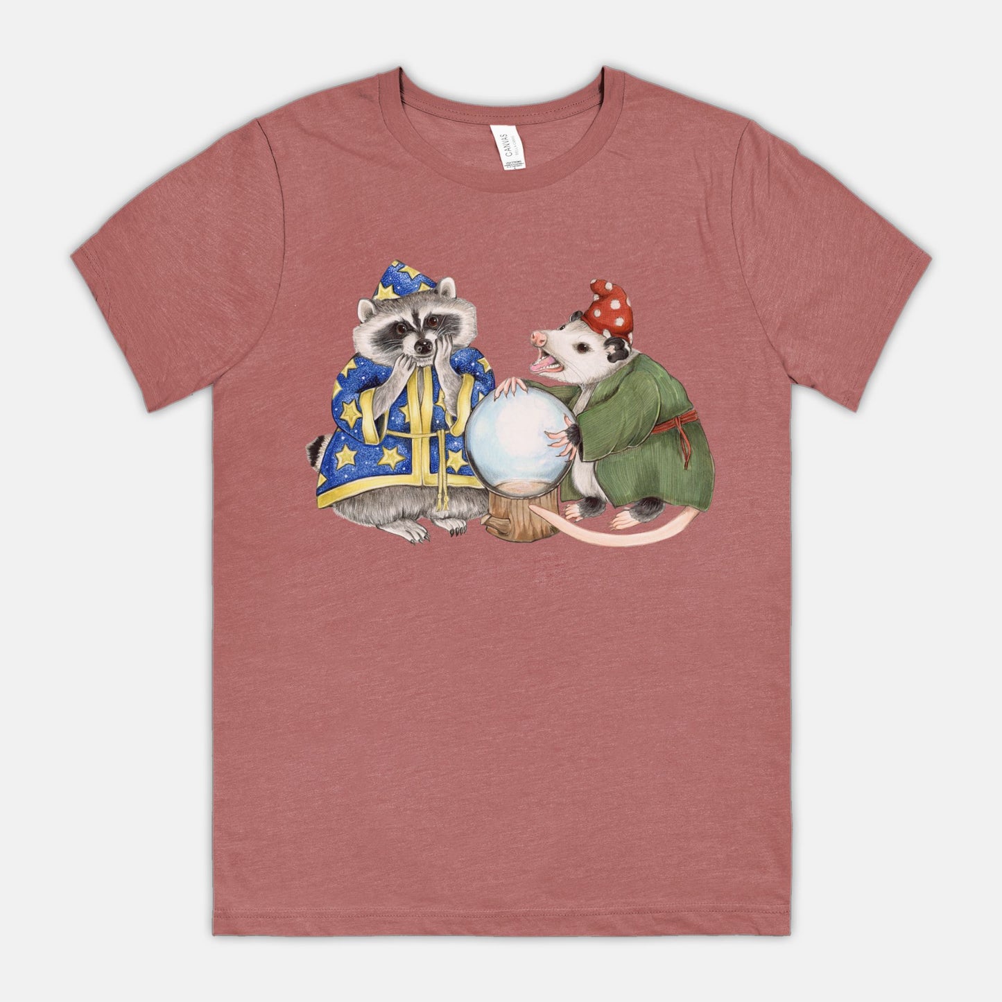 A mauve t-shirt featuring an illustration of a raccoon wizard and opossum fortune teller