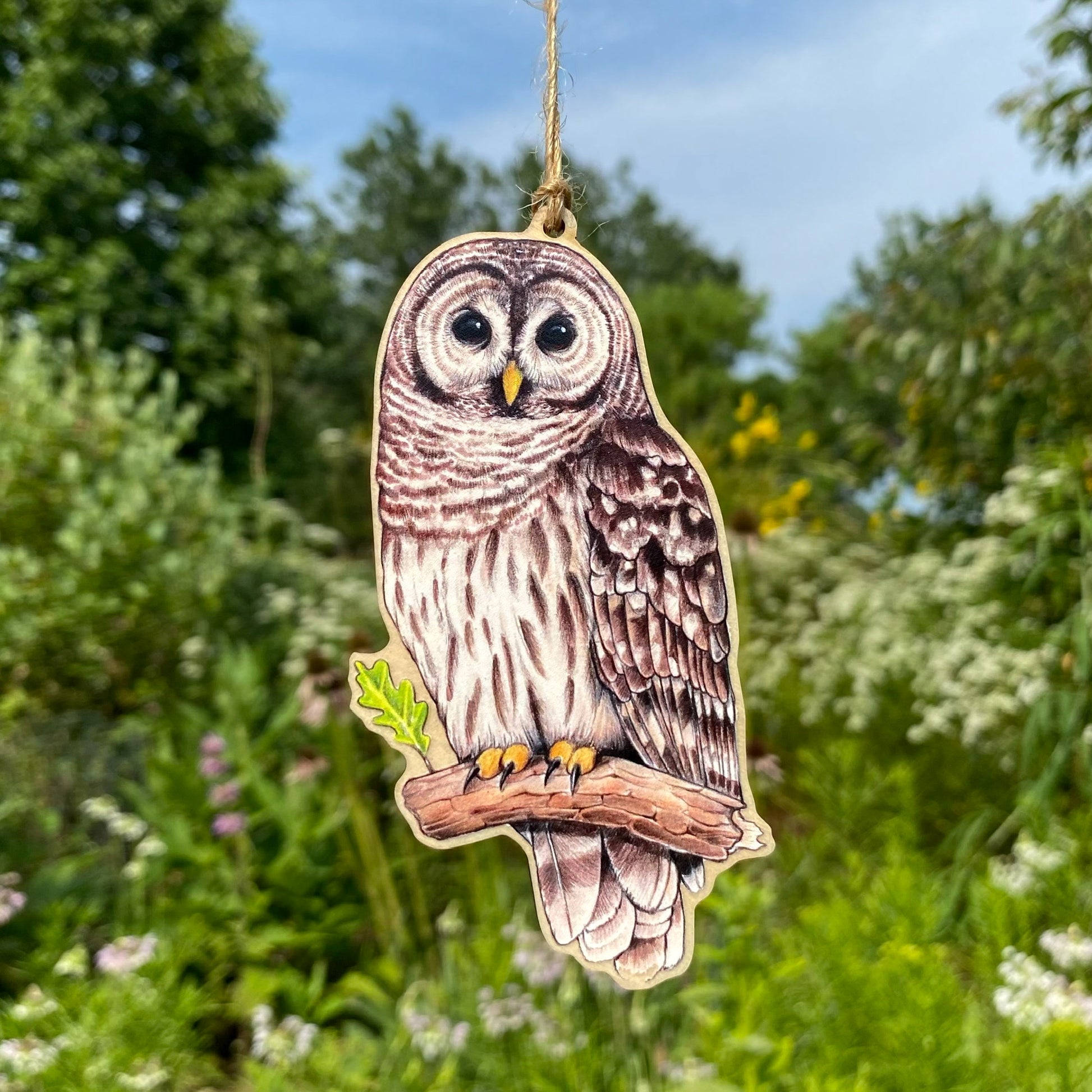 A wooden ornament strung with twine of a barred owl.