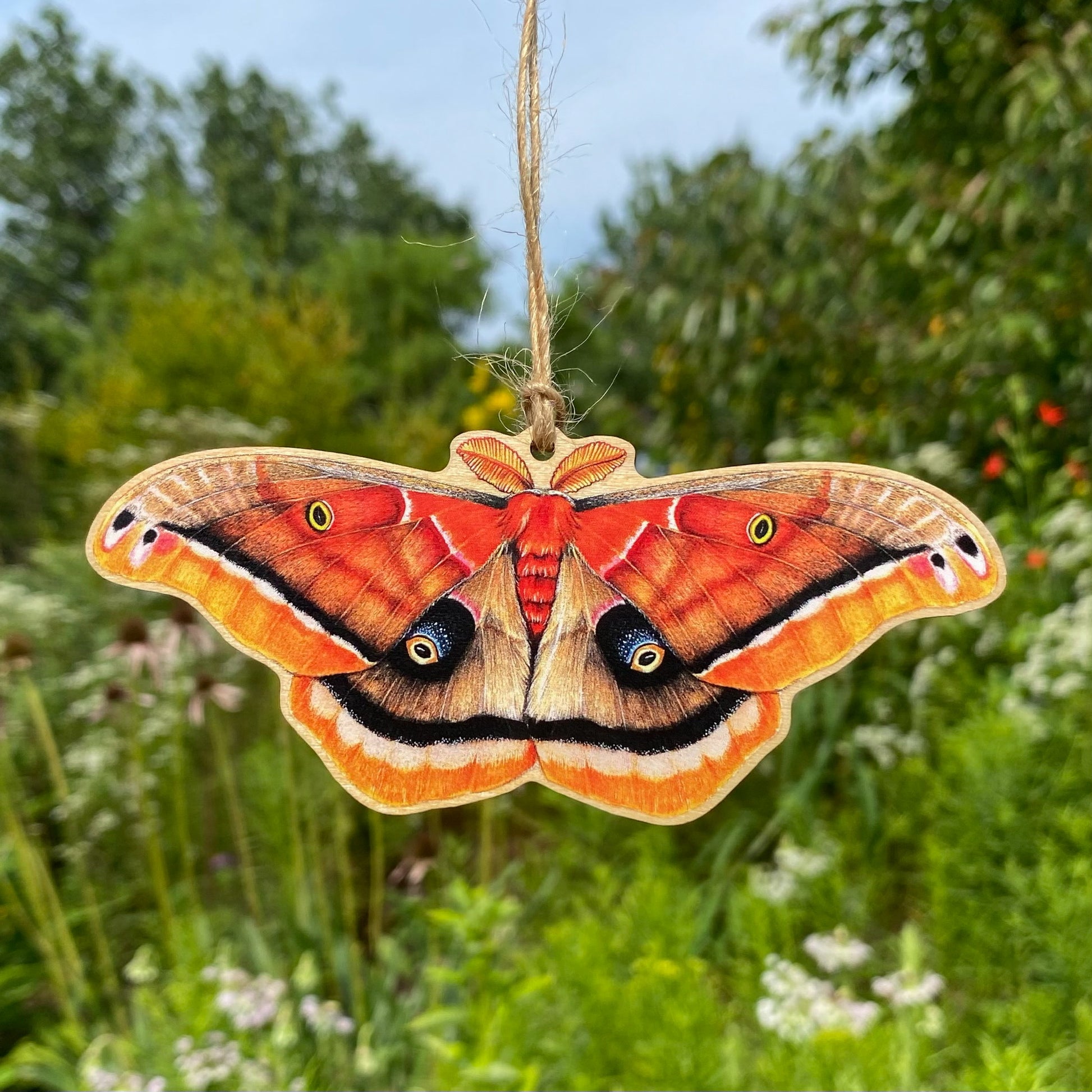 A wood print ornament featuring an illustration of a Polyphemus moth