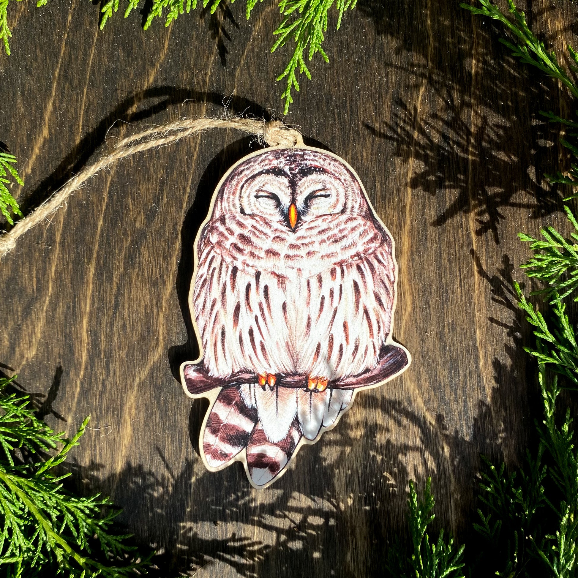 A wood print ornament featuring an illustration of a barred owl