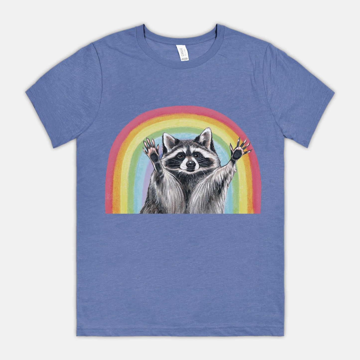 A blue t-shirt featuring an illustration of a raccoon with raised hands in front of a rainbow.