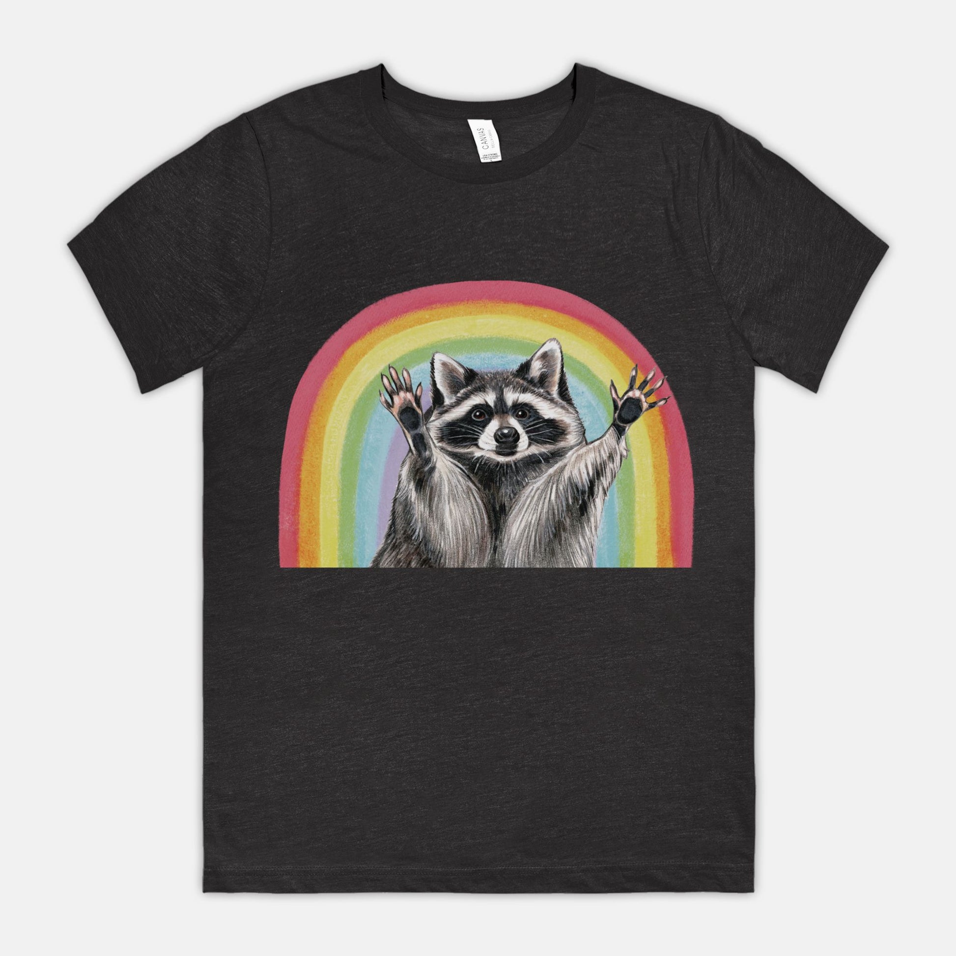 A black t-shirt featuring an illustration of a raccoon with raised hands in front of a rainbow.