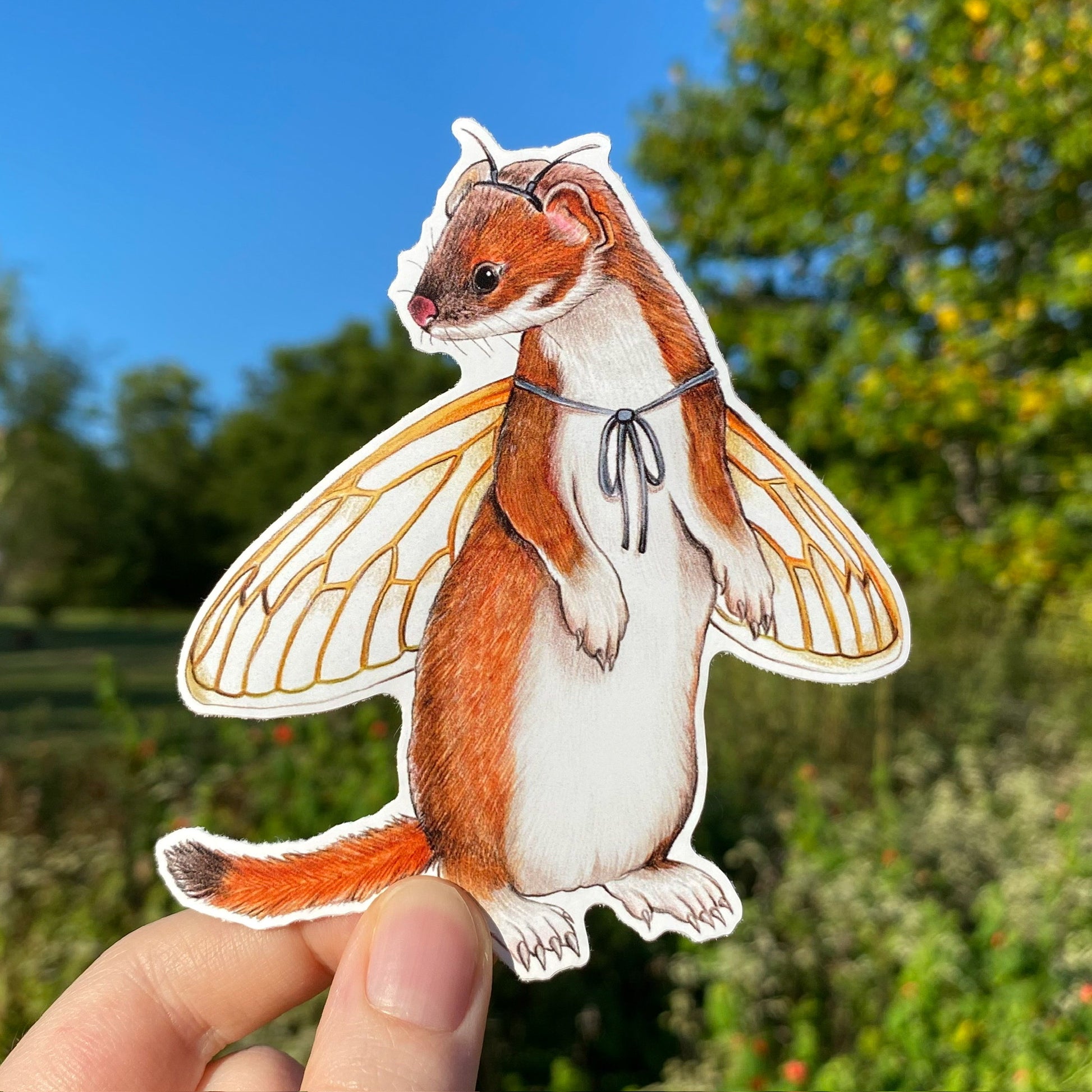 A hand holding a weatherproof vinyl sticker of a stoat with periodical cicada wings.