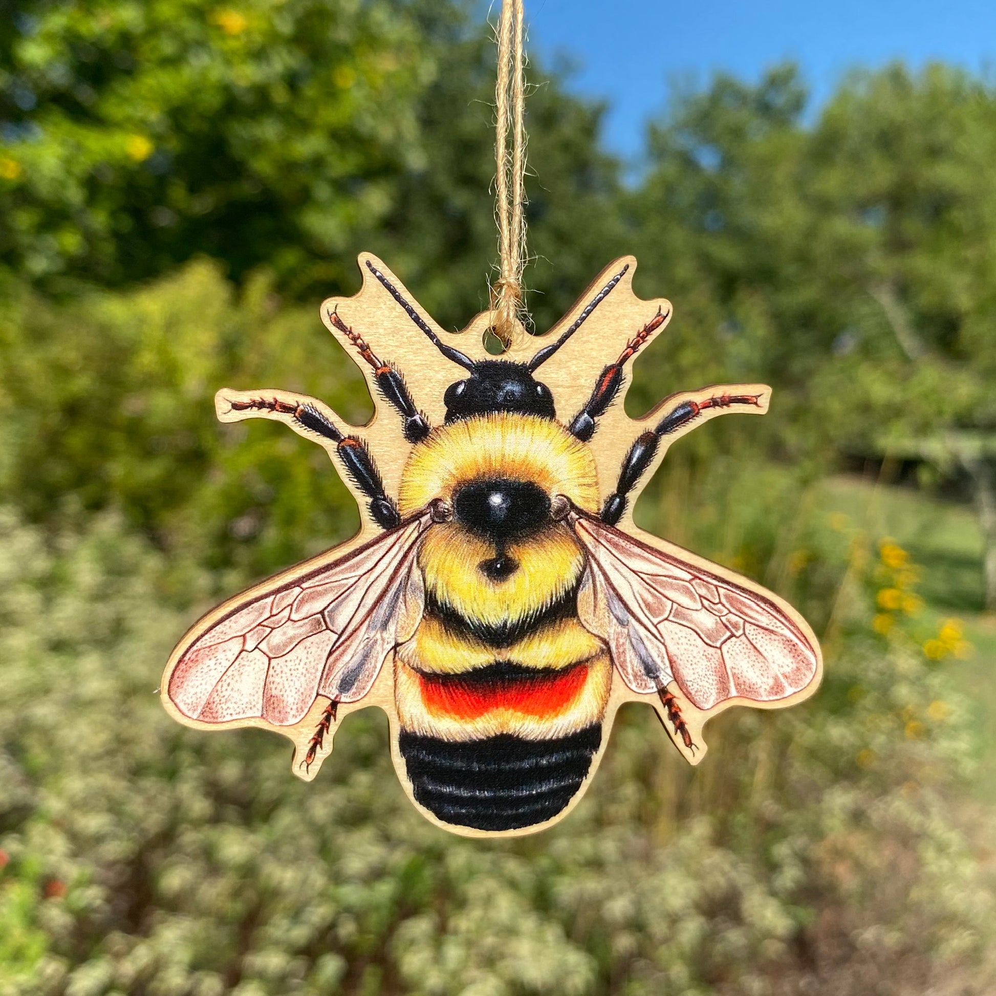 A wooden ornament strung with twine of a rusty-patched bumble bee.