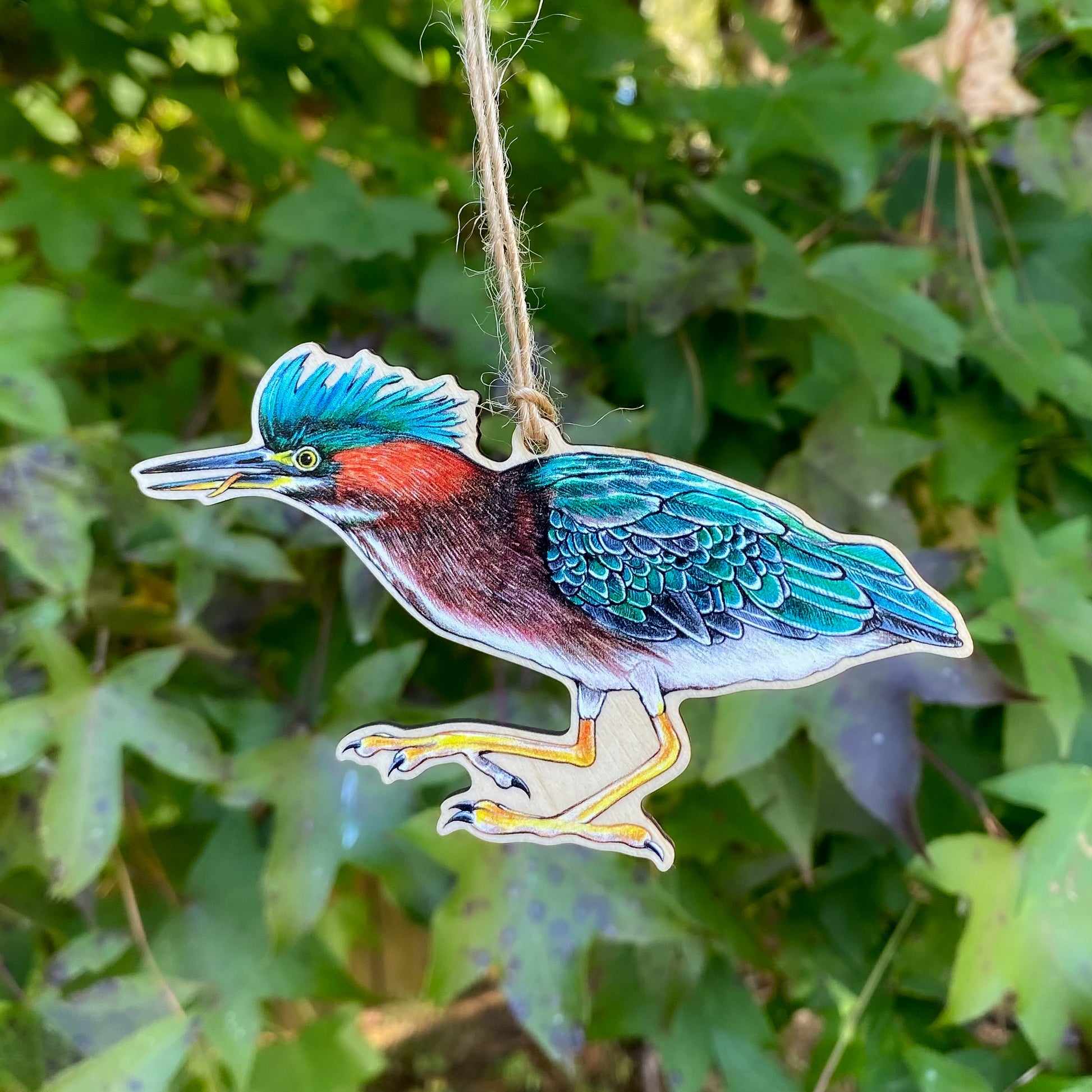 A wooden ornament strung with twine of a green heron.