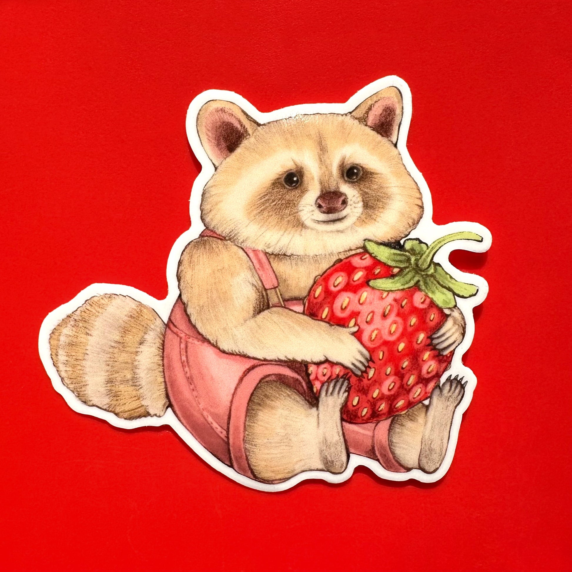 A sticker of a blond raccoon in pink overalls holding a strawberry on a white background on a red background.