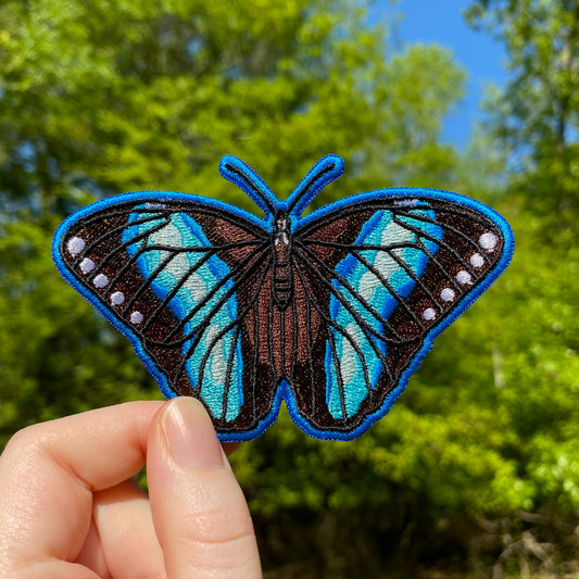 An embroidered patch of a blue Achilles Morpho butterfly. 