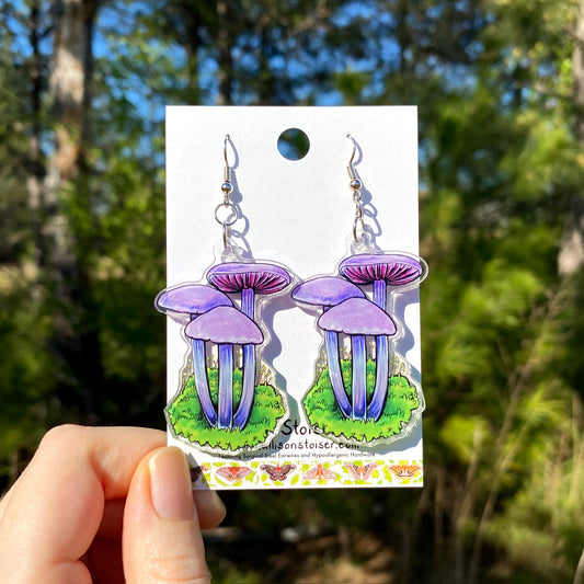 A pair of acrylic earrings of amethyst deceiver mushrooms.