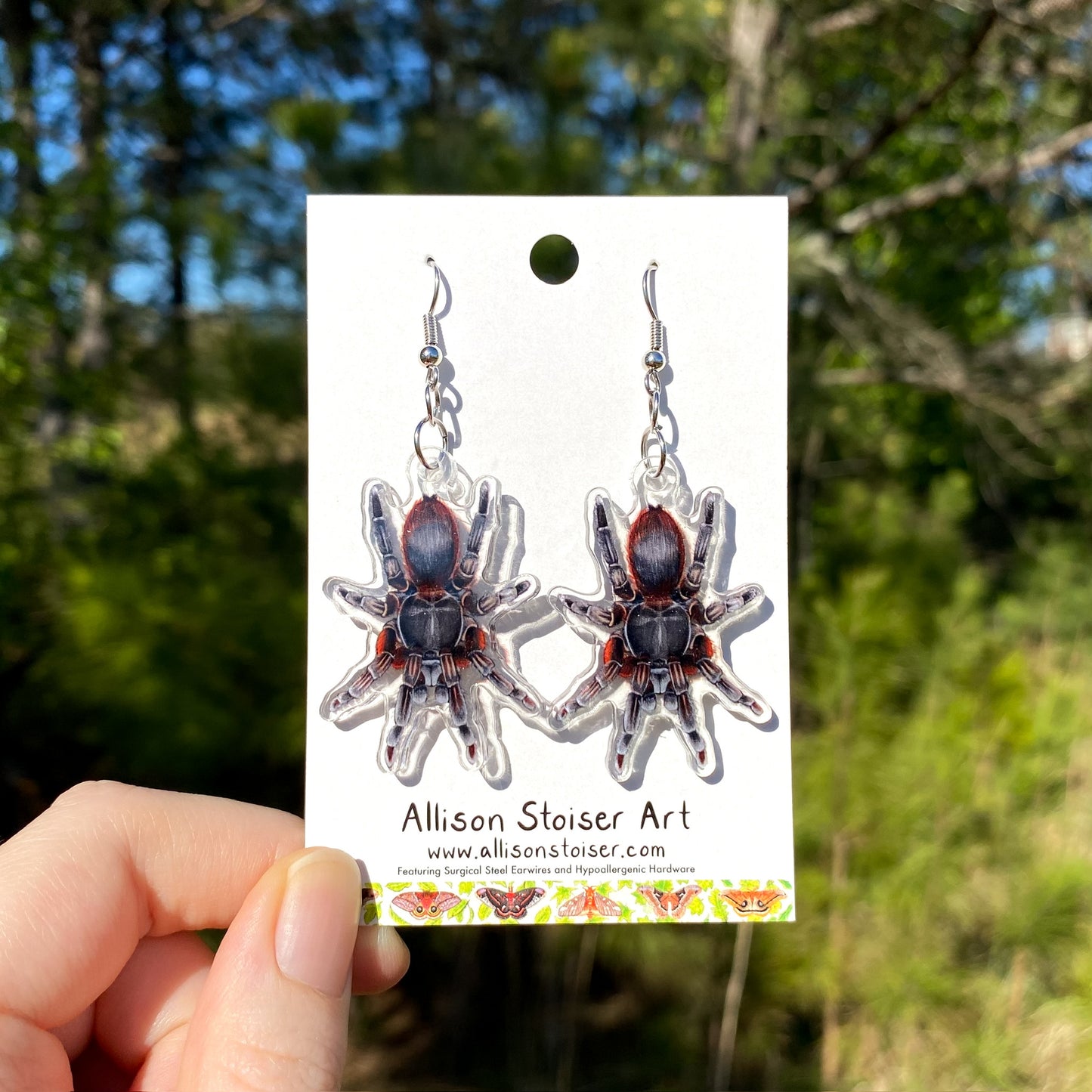 A pair of acrylic charm earrings of tarantulas.