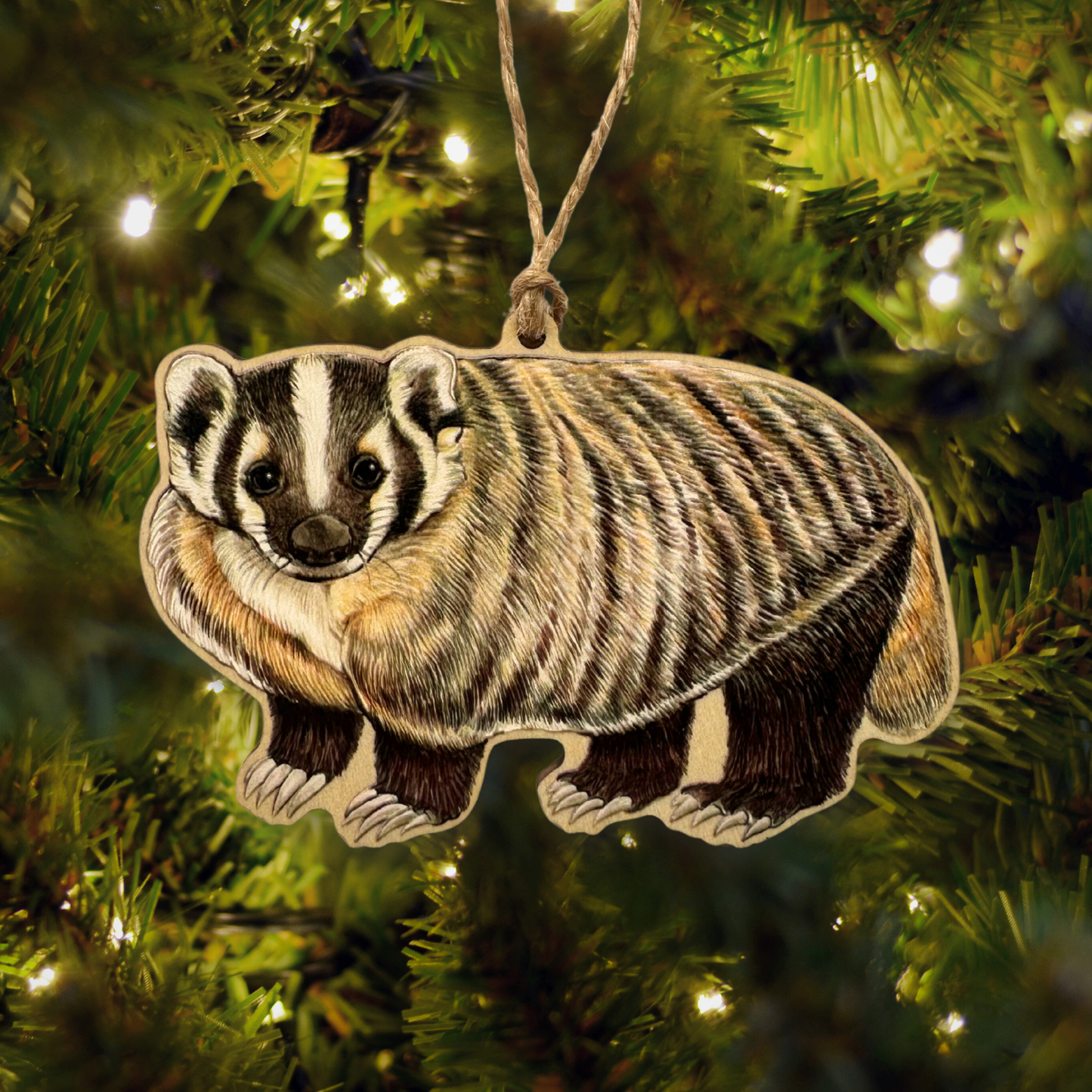 Badger ornament hanging on a Christmas tree with lights in the background