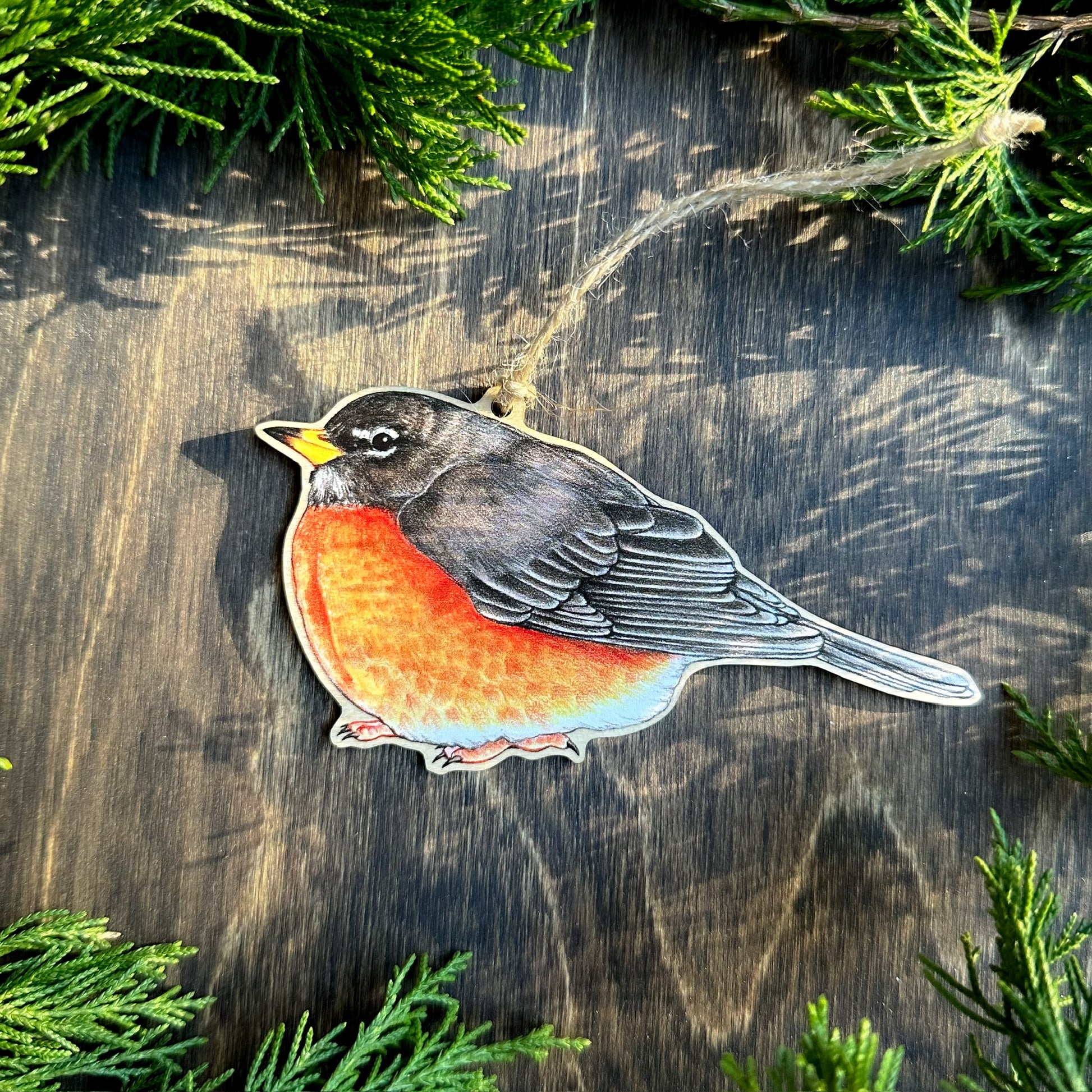 American robin ornament on a wooden surface with greenery around