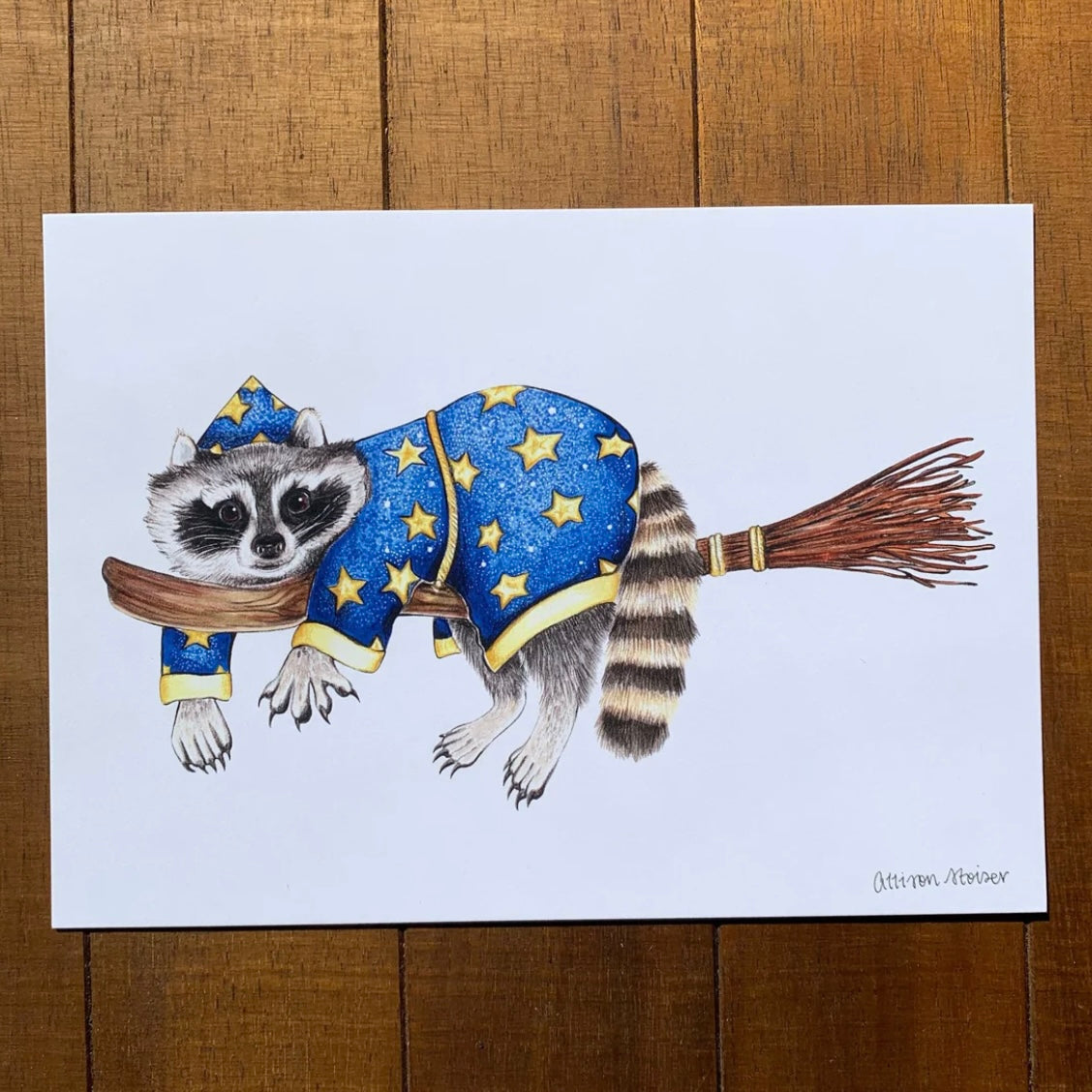 A print featuring a wizard raccoon riding a broom