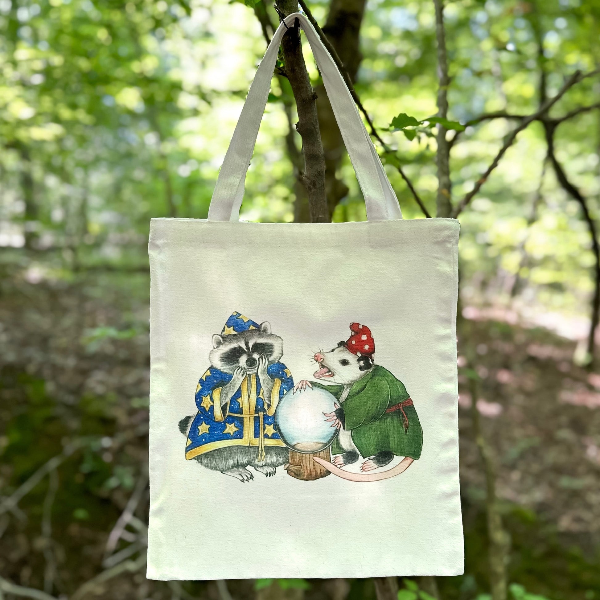 A tote bag featuring an illustration of raccoon and opossum wizards