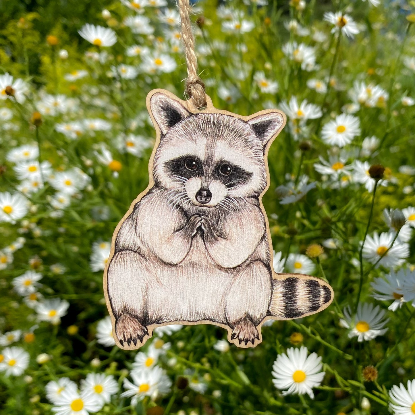 Baby raccoon ornament hanging among white flowers