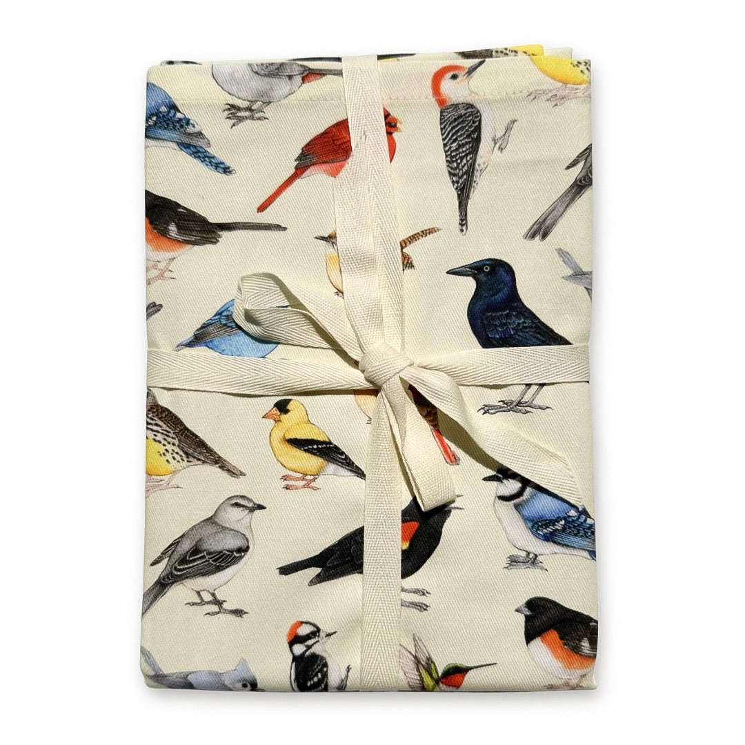 A ribbon-wrapped tea towel featuring a cream-colored fabric with a backyard bird pattern on a plain white background