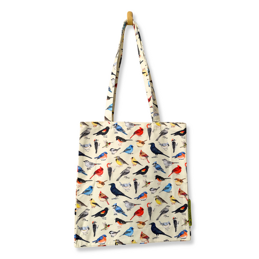 A canvas tote bag with a backyard bird pattern on a cream background, hanging from a wooden peg on a white wall.